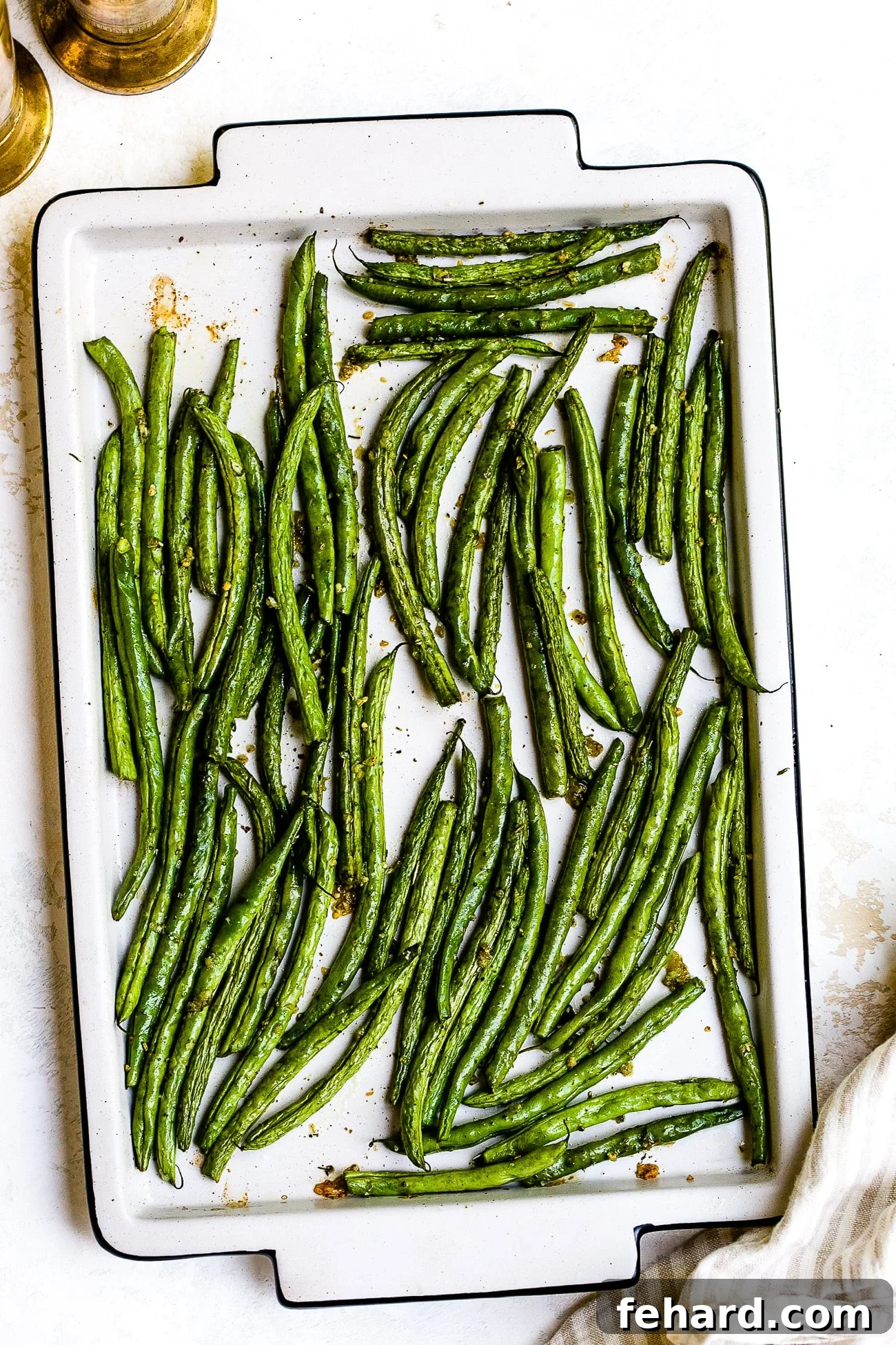Roasted green beans on a baking sheet, golden and crisp.