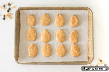 Twelve perfectly shaped homemade peanut butter eggs on a parchment-lined baking sheet.
