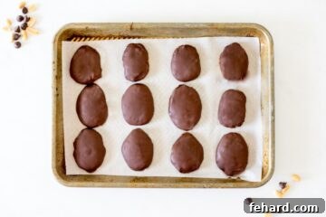 Chocolate-dipped homemade peanut butter eggs on a parchment-lined baking sheet.