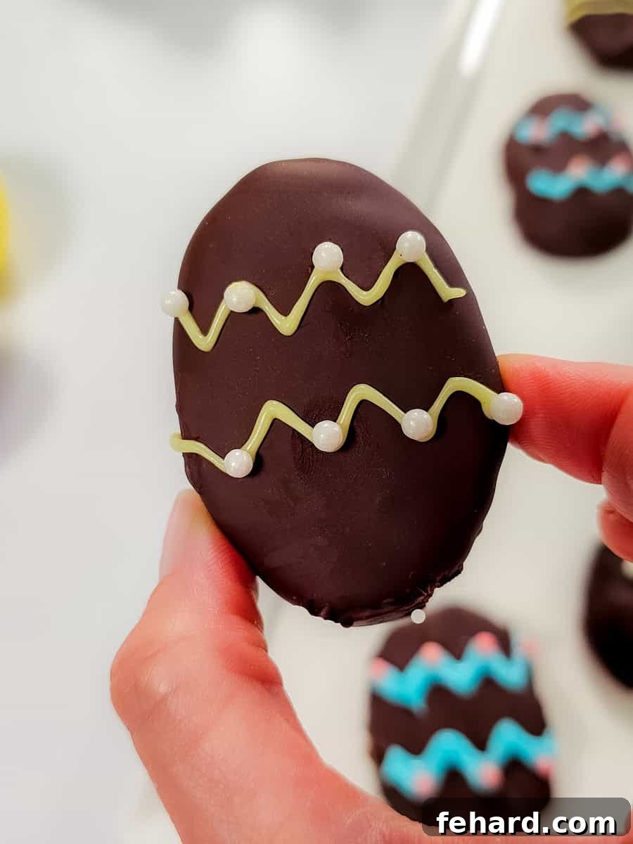 A decorated homemade peanut butter egg, held carefully, showcasing colorful icing and sprinkles against a soft background.