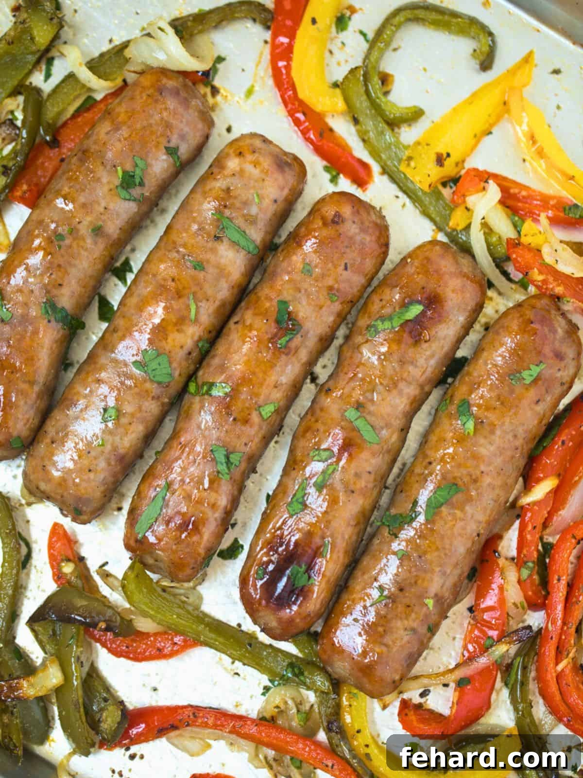 Baked Italian sausage and peppers sheet pan dinner Perfectly baked Italian sausages with colorful bell peppers and onions, garnished with fresh parsley on a baking sheet, ready to serve.