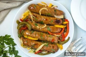 Baked Italian sausage in white serving dish topped with peppers and onions and minced parsley.