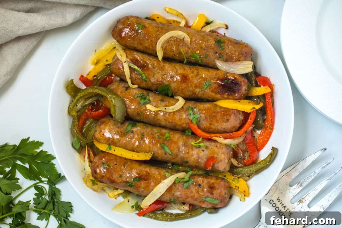 Italian Sausage Sheet Pan Recipe Serving A white serving dish filled with baked Italian sausage, roasted peppers, and onions, garnished with fresh minced parsley.