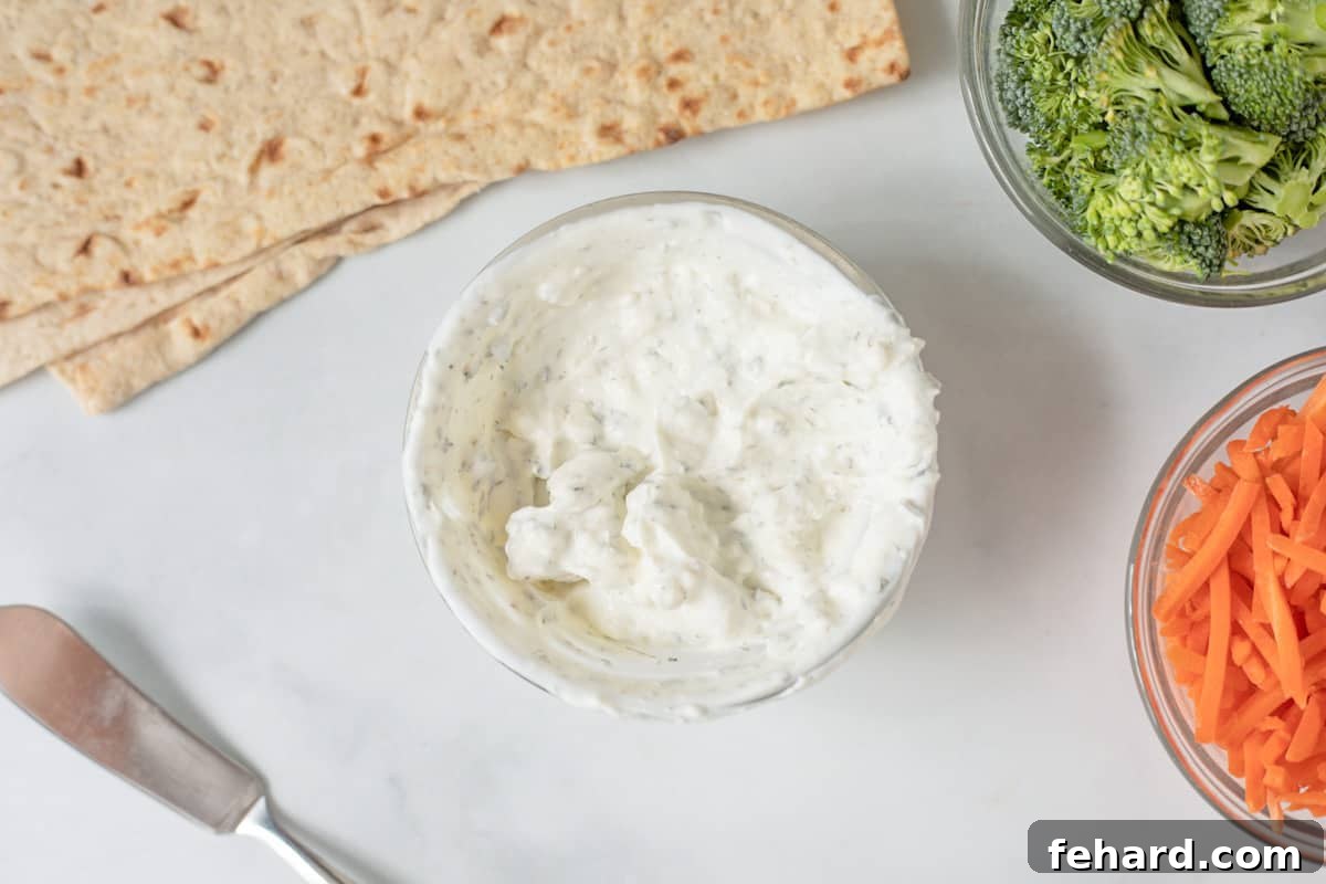 Easy Vegetable Wrap Preparation Bowl of creamy ranch spread next to tortillas and sliced carrots, ready for assembly.