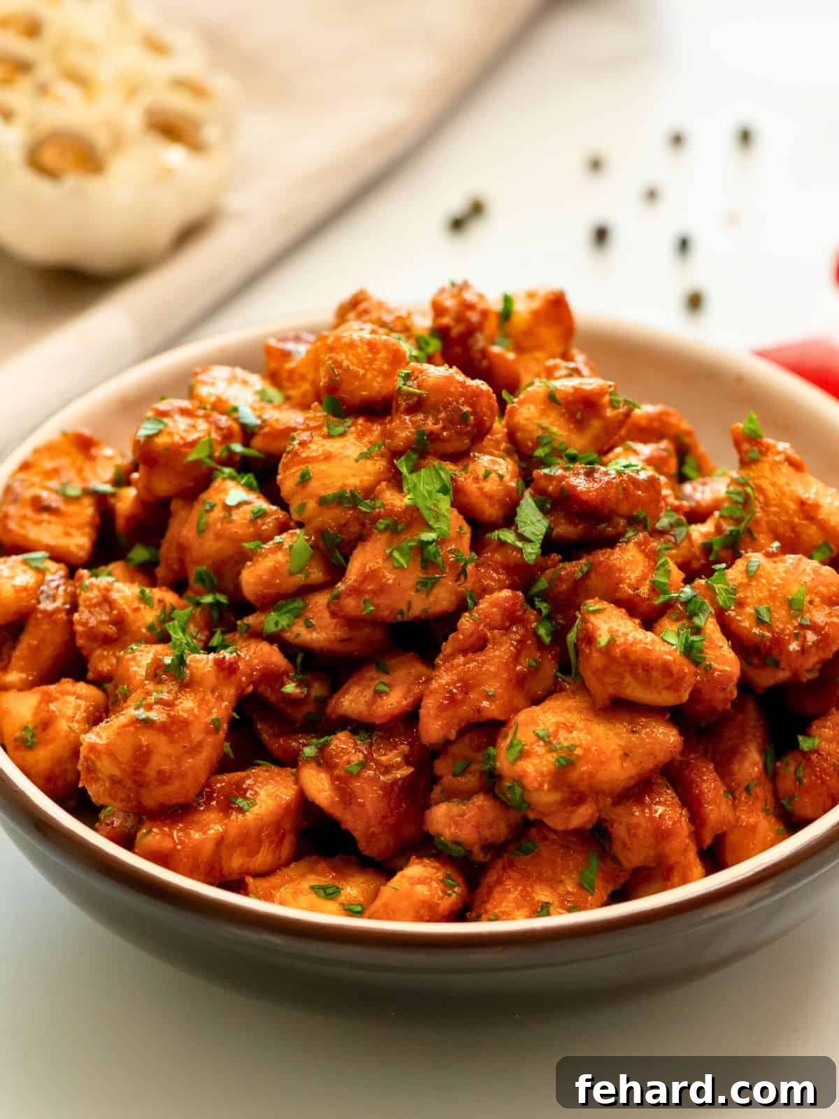 Caramelized spice-rubbed chicken bites served in a large bowl, garnished with fresh parsley.