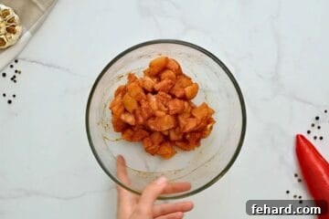 Cubed chicken breast in a large mixing bowl, thoroughly seasoned with a sweet and savory spice rub.