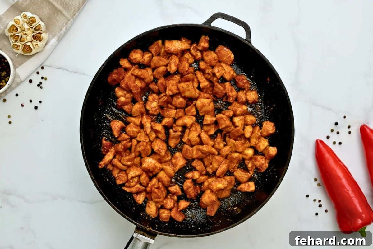 Browned chicken bites in a skillet, coated with a sweet and savory glaze.