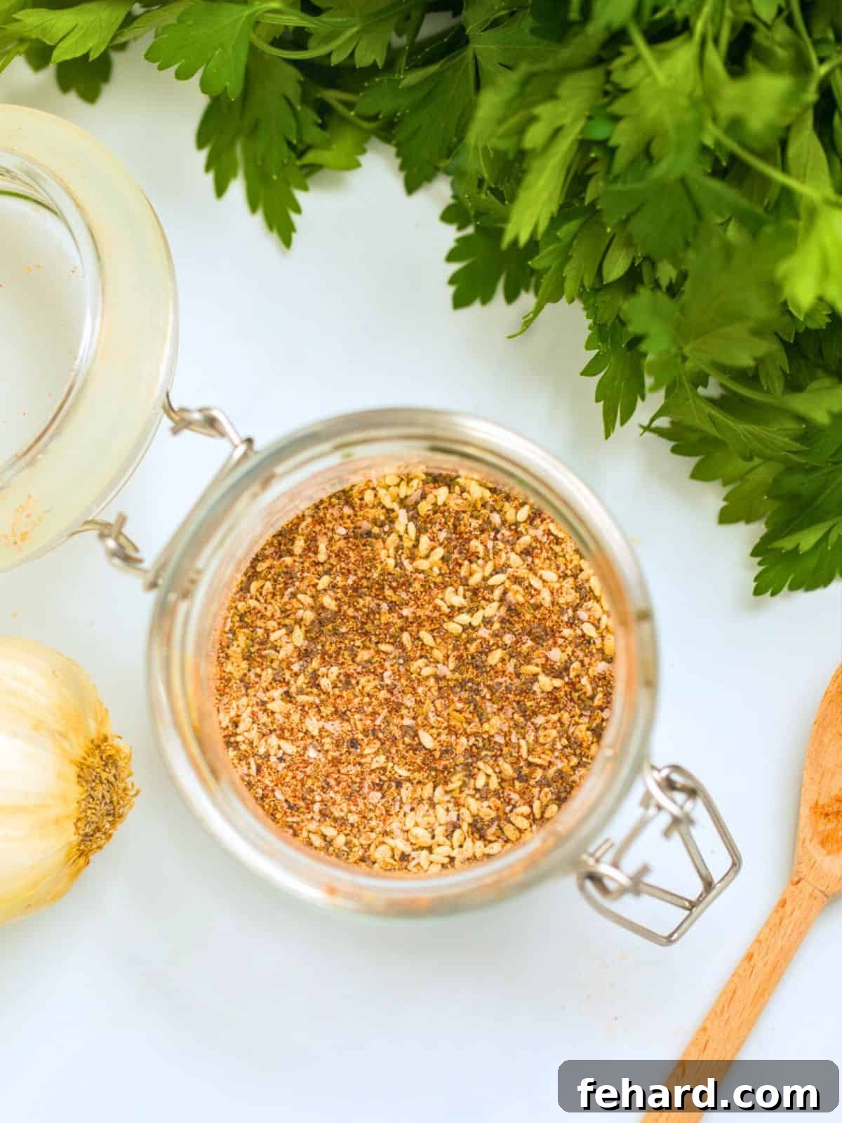 Homemade Salad Supreme Seasoning Recipe Homemade Salad Supreme Seasoning in a clear glass spice jar, elegantly displayed next to fresh garlic cloves and a rustic wooden spoon on a kitchen counter, highlighting natural ingredients.