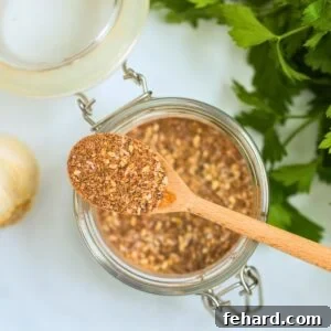 Homemade blend of spices and grated cheese in small jar next to parsley to make copycat version of Salad Supreme Seasoning.