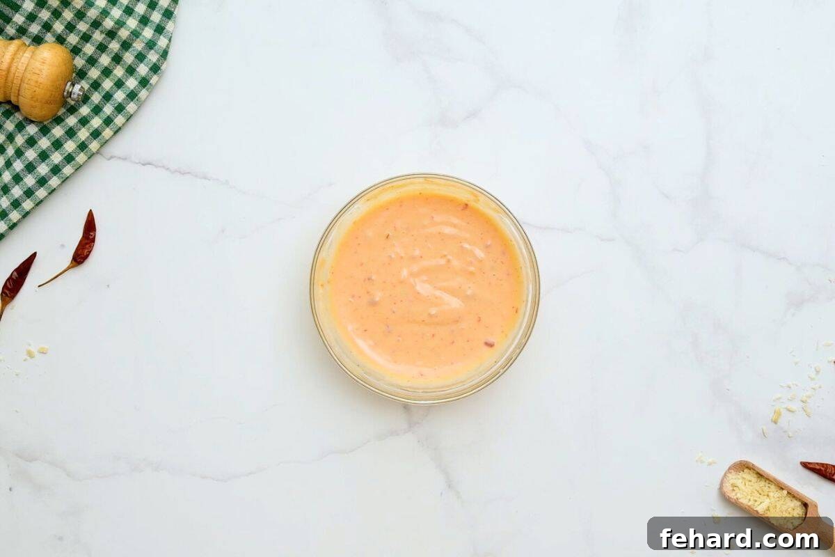 Mayonnaise, sweet Thai chili sauce, and sriracha mixed together in a small bowl, showing the creamy, uniform consistency of Bang Bang Sauce.