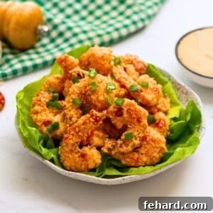 Baked Crispy Bang Bang Shrimp served on bibb lettuce leaves topped with minced green onions and bang bang sauce on the side.
