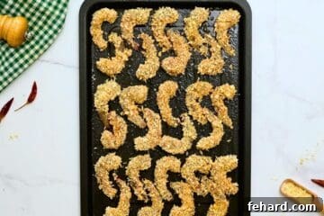 Expertly breaded raw shrimp arranged in a single, non-overlapping layer on a greased baking sheet, poised for baking.