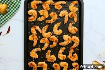 A baking sheet showcasing golden-brown, crispy baked breaded shrimp, perfectly cooked and ready for saucing.