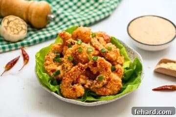 Crispy Breaded Shrimp artfully arranged on crisp bibb lettuce leaves, beautifully garnished with minced green onions, with the signature Bang Bang sauce served on the side for dipping, ready to be enjoyed.