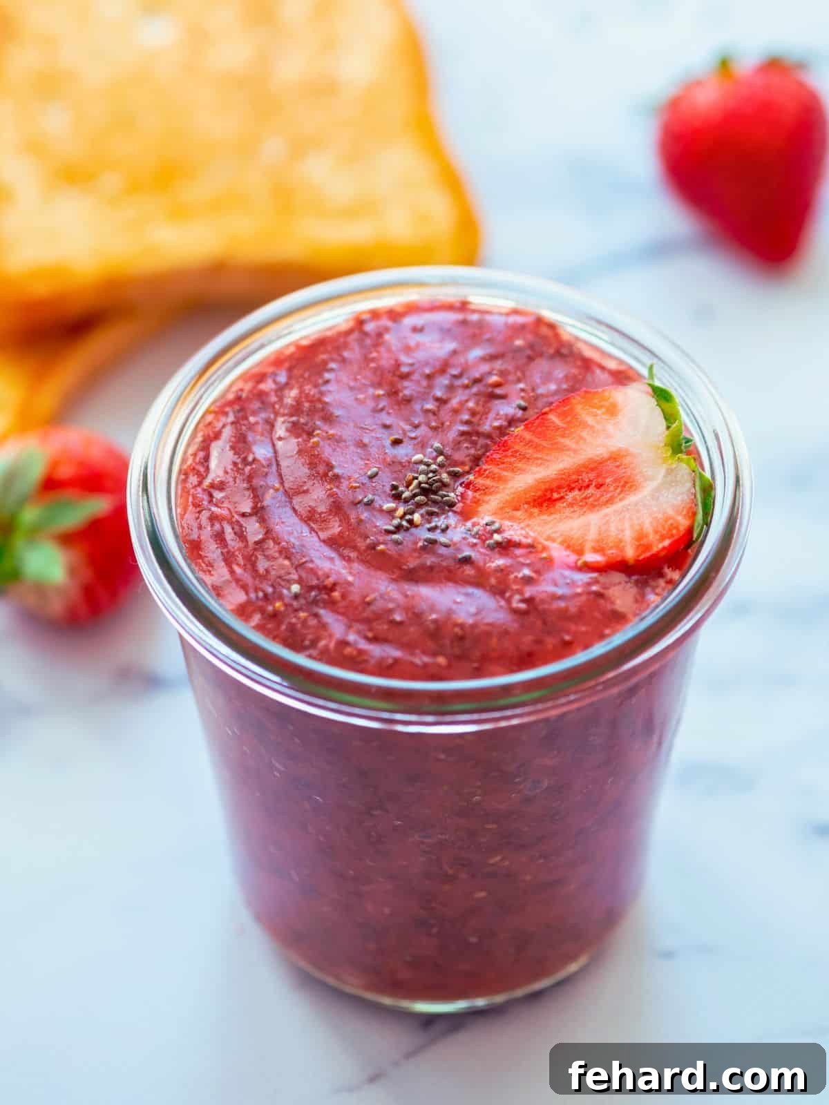 Jar of homemade strawberry chia jam with fresh berries in background.