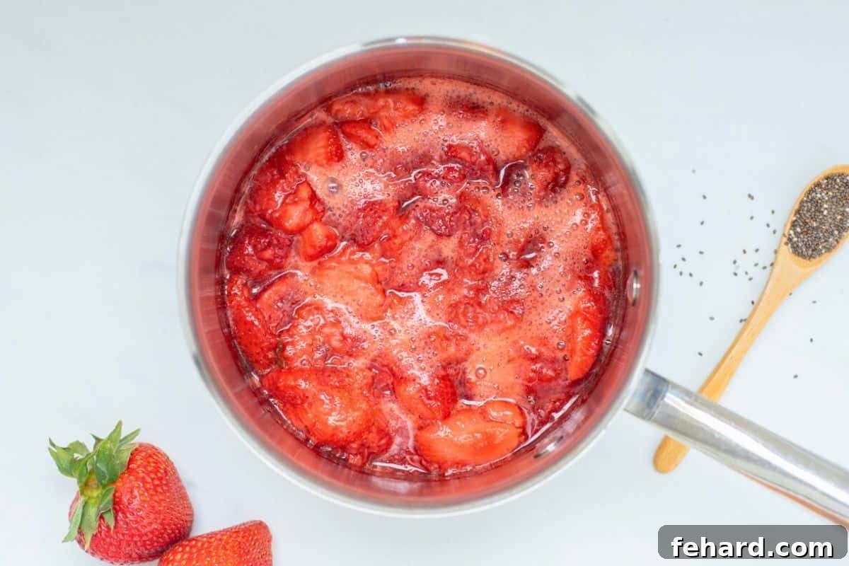 Strawberries in saucepan after simmering with maple syrup and beginning to break down.