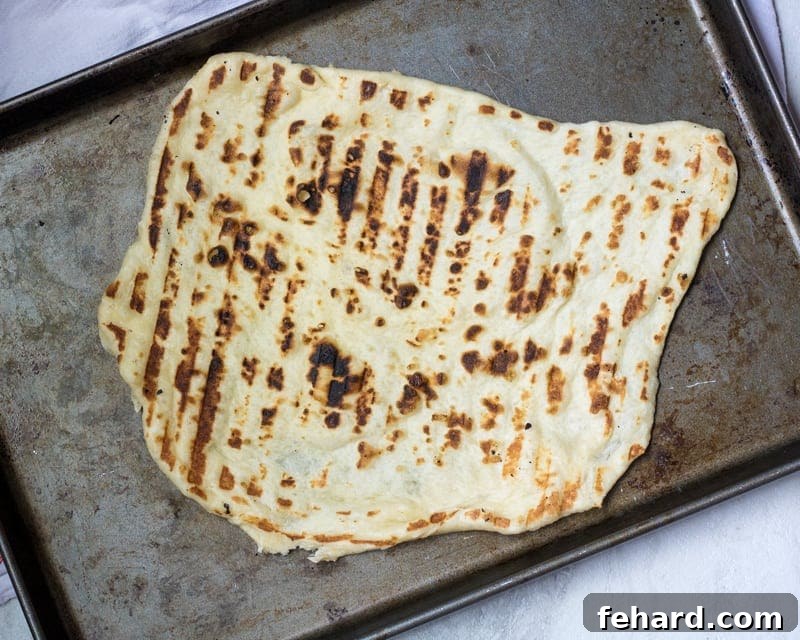 Perfectly grilled pizza dough with subtle char marks, ready for toppings.