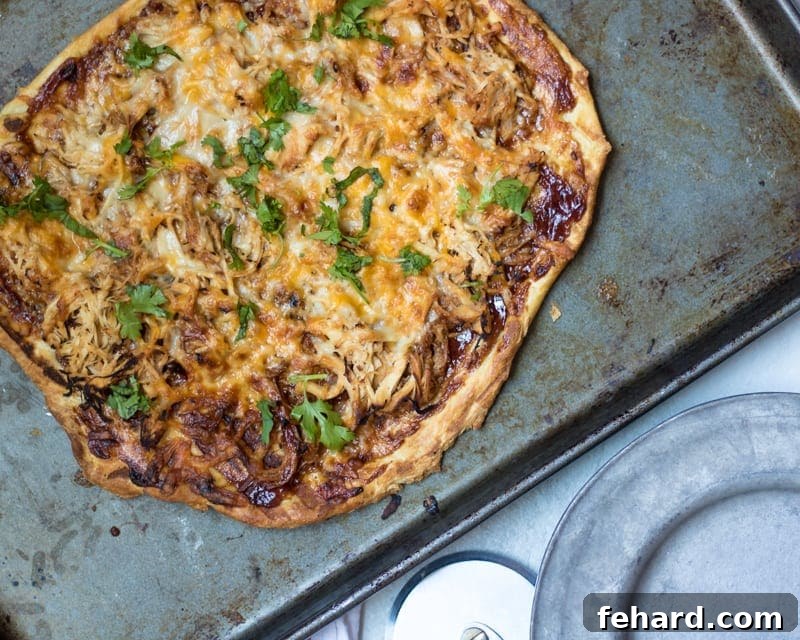Finished Pulled Pork Grilled Pizza, hot and ready to be sliced, with melted cheese and fresh cilantro.