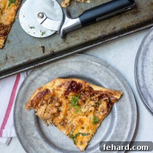 Close-up of a delicious Pulled Pork Pizza on a silver plate, showing the texture of the pork and melted cheese.