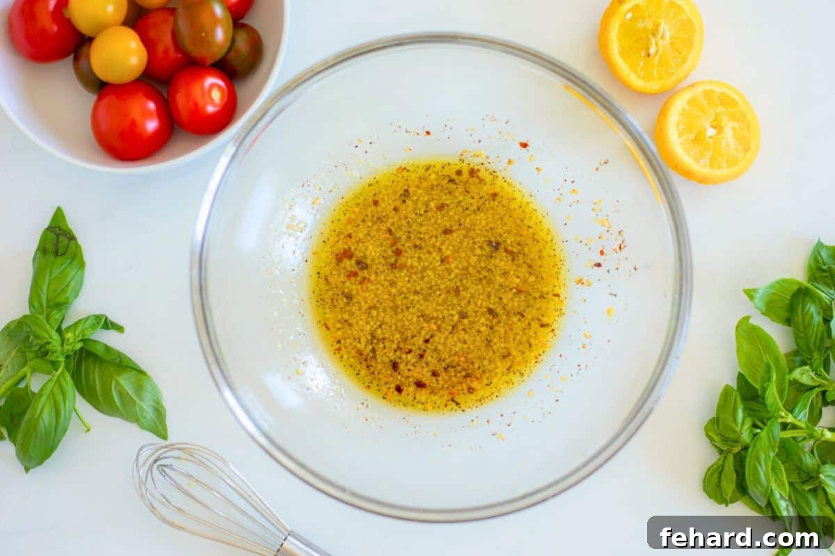 Lemon Garlic Dressing for Zucchini Salad A large glass mixing bowl filled with freshly prepared lemon garlic dressing, surrounded by fresh basil leaves, ready to be combined with the salad ingredients.