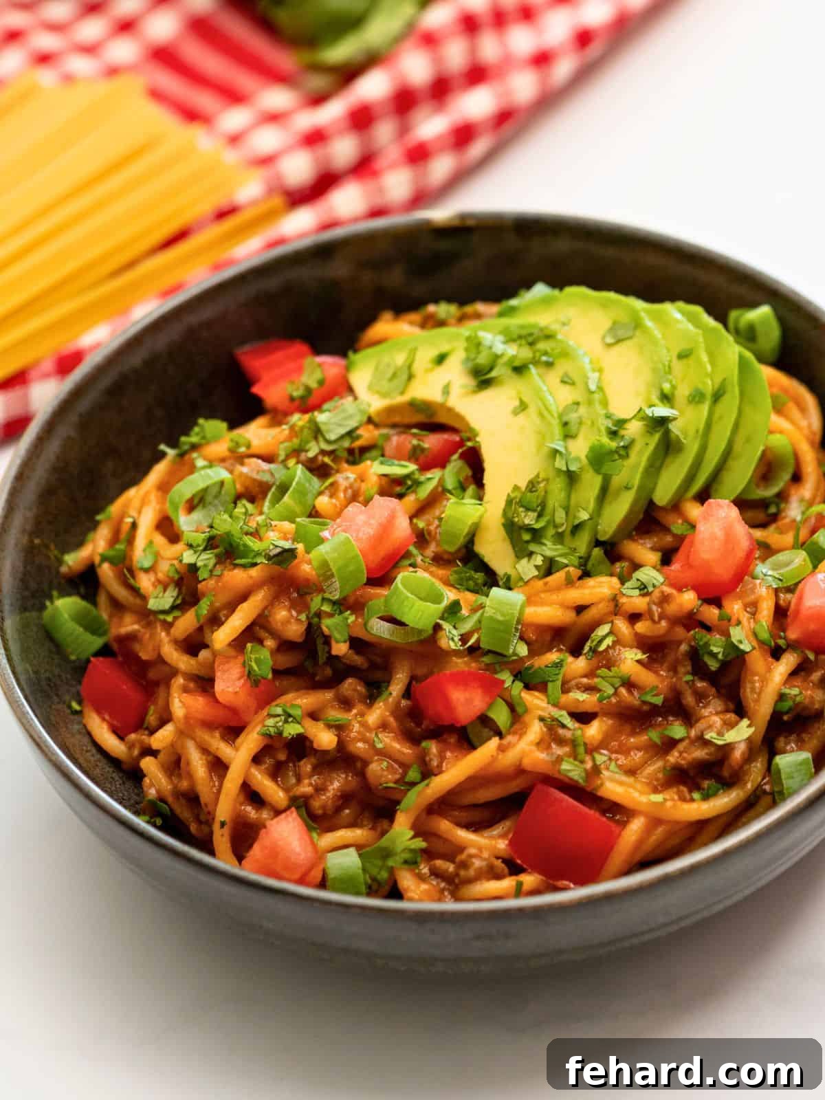 Mexican Spaghetti Recipe Bowl of Mexican Spaghetti topped with cilantro, avocado, and diced tomatoes.