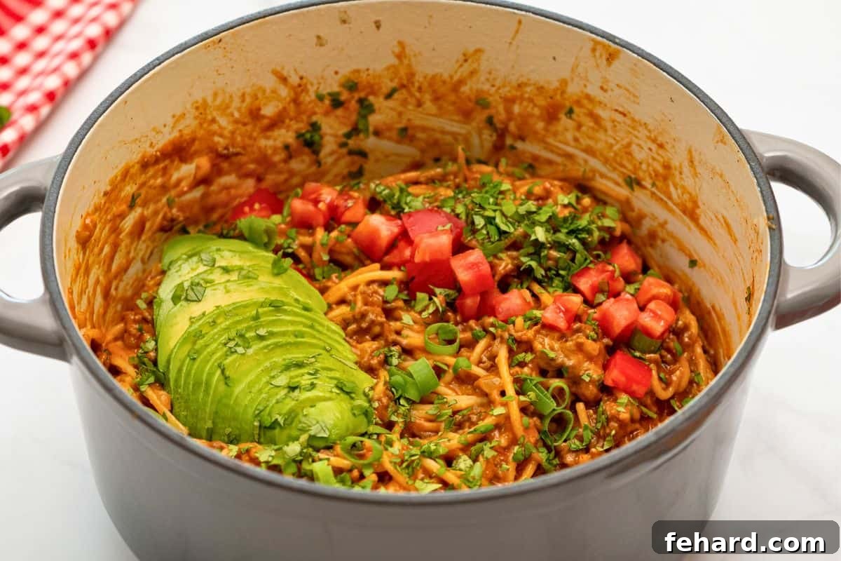 One Pot Mexican Spaghetti Pan of Mexican Spaghetti topped with cilantro, avocado, and diced tomatoes.