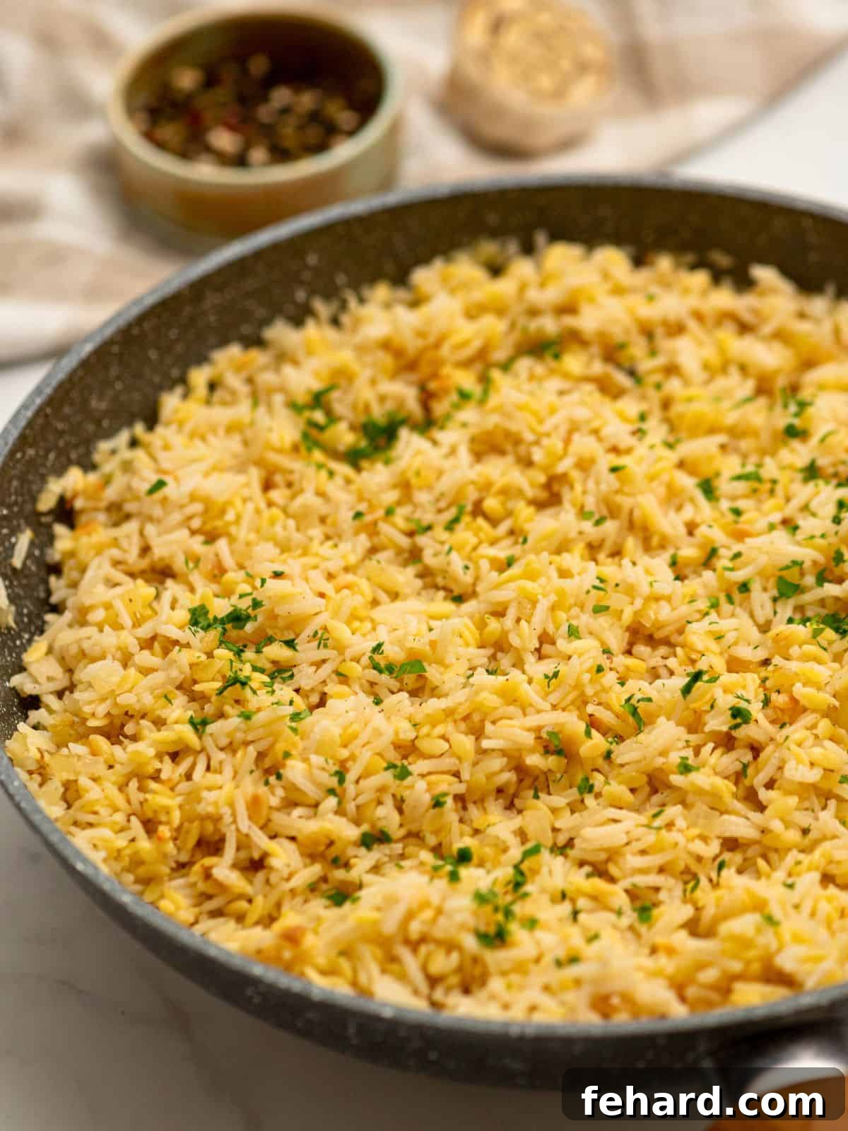 Sauté pan with orzo rice pilaf topped with fresh minced parsley.