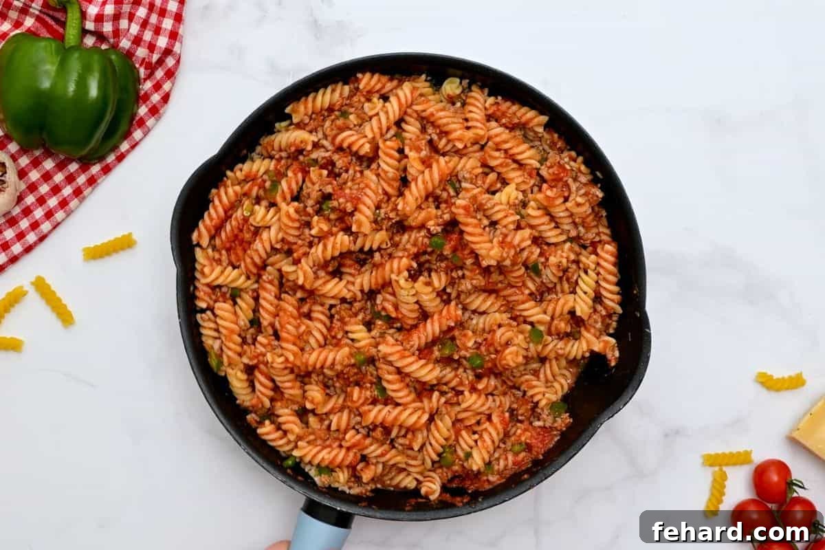 Cooked pasta tossed with marinara and ground sausage in large skillet.