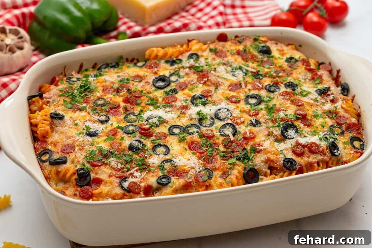 Pasta bake topped with pizza sauce, cheese, olives, and pepperoni in casserole dish baked until cheese is golden.
