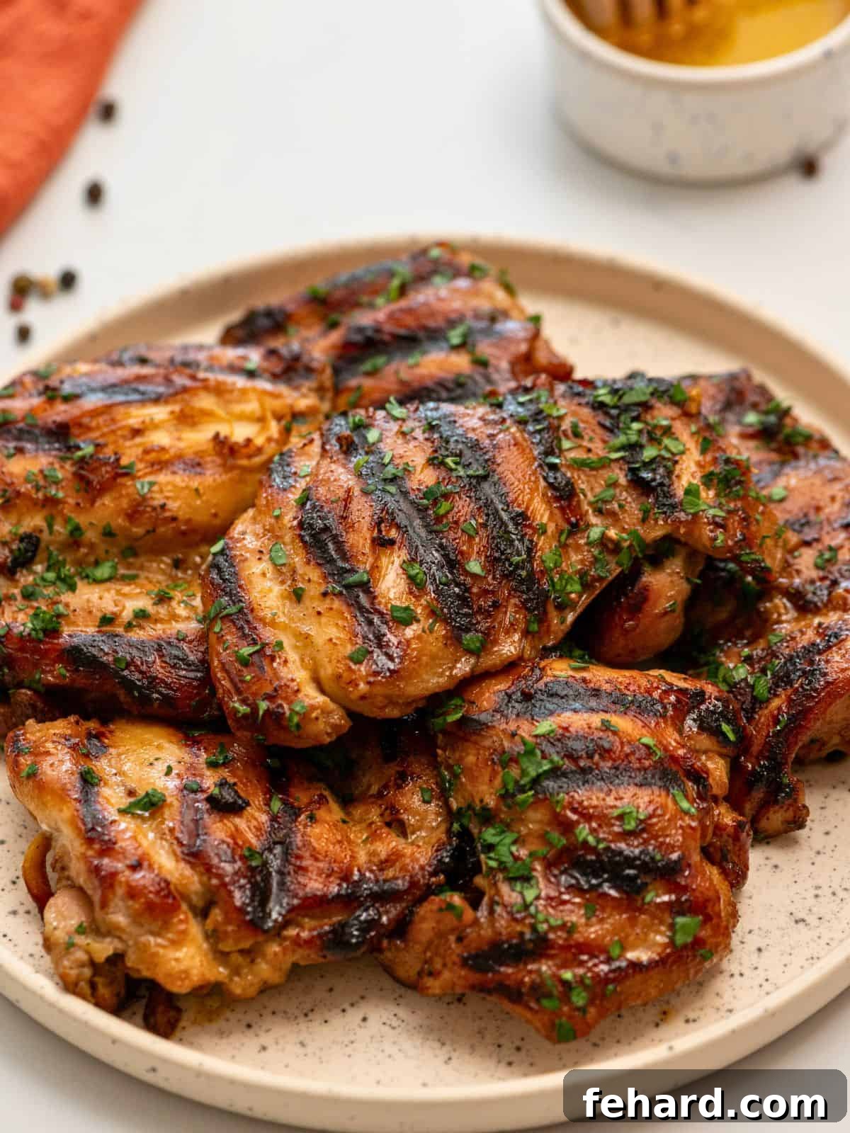 Marinated grilled chicken thighs on platter topped with minced parsley, showcasing juicy, tender perfection.