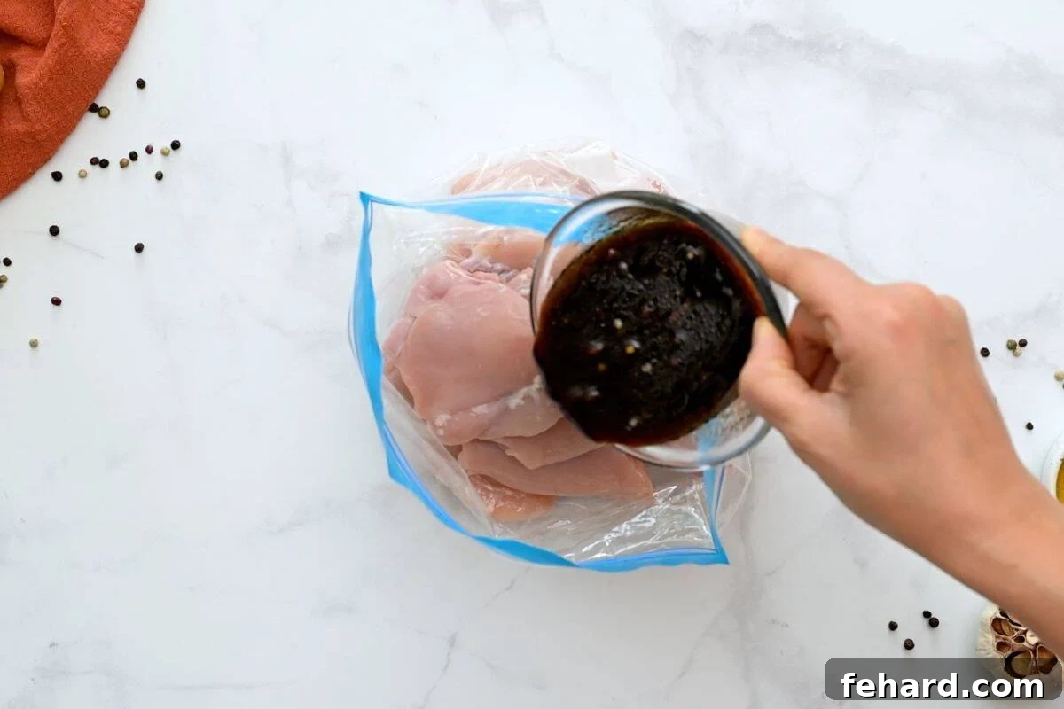 Marinade being poured over chicken thighs in large storage bag, ensuring even coating.