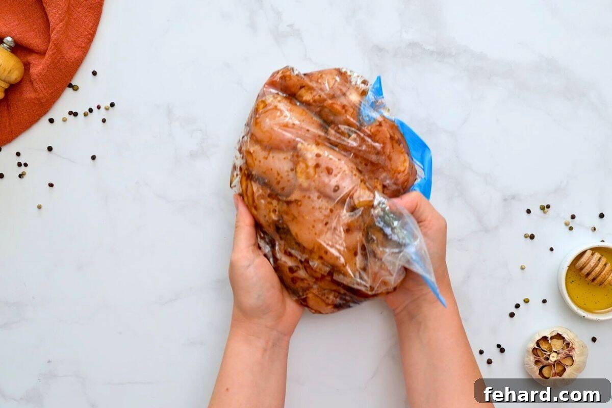Chicken thighs and chicken thigh marinade in large storage bag after being tossed to coat chicken with honey soy marinade, ready for refrigeration.