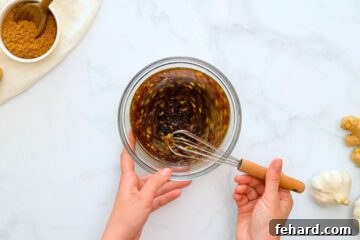 Homemade Teriyaki Sauce being whisked in small mixing bowl next to fresh garlic.