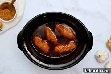 Slow Cooker filled with cooked chicken breasts in homemade teriyaki sauce.