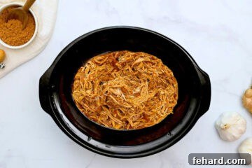 Shredded Chicken tossed with teriyaki sauce inside slow cooker.