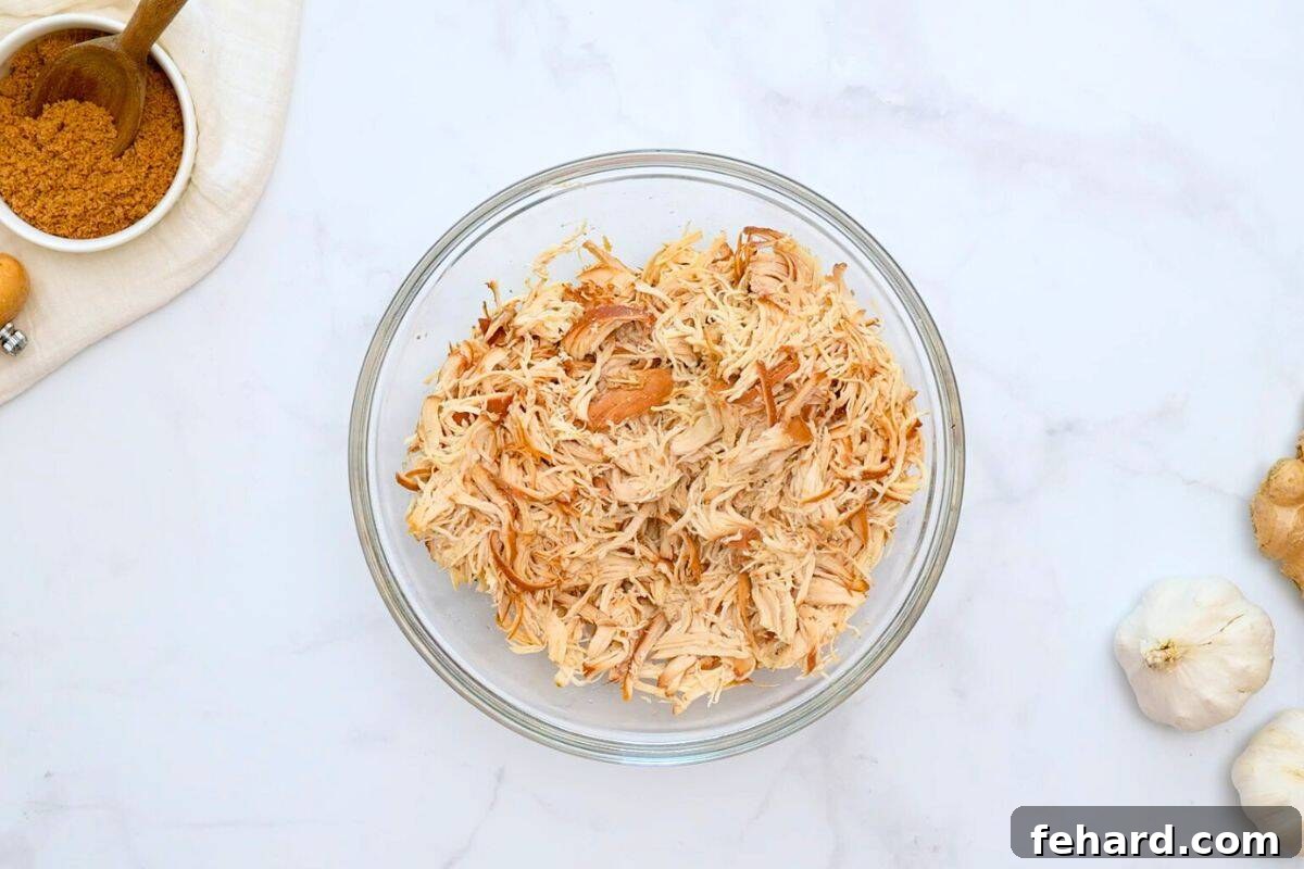Shredded crockpot chicken in a large mixing bowl, ready for the sauce.