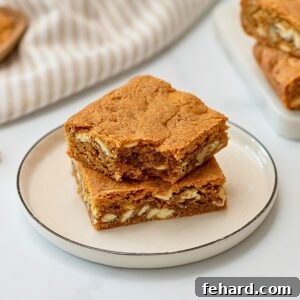 Two soft, chewy Brown Butter Blondies, enriched with white chocolate chips and walnuts, perfectly cut into squares and arranged invitingly on a white plate. Each blondie showcases its signature crinkly top and golden-brown edges.