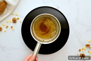 Small saucepan with butter that has melted and turned slightly golden and solids at bottom of pan.