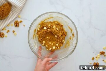 Blondie batter with white chocolate chips and walnuts in a large mixing bowl, showcasing the thick texture and ready for spreading.