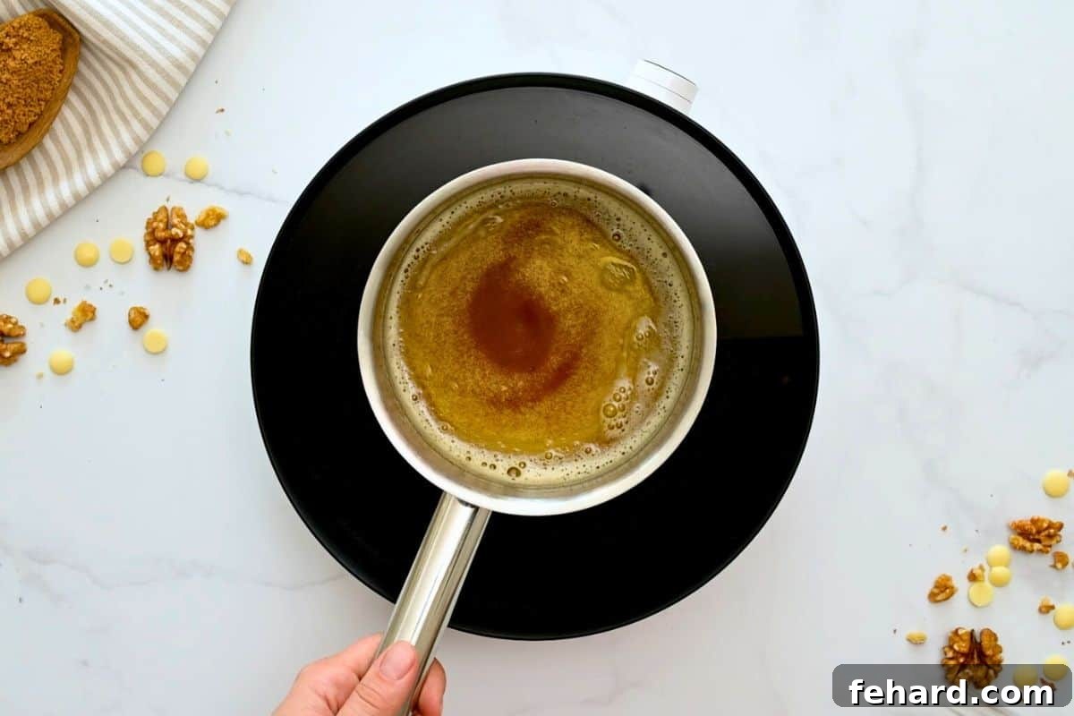 A small saucepan on the stove containing melted butter that has turned a rich golden-amber color with delicious brown milk solids visible at the bottom, indicating perfect browning.