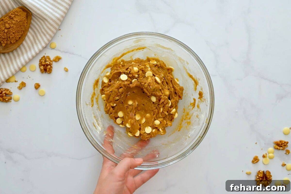The rich blondie batter, now complete with generous white chocolate chips and walnuts, resting in a large mixing bowl, beautifully textured and ready for baking.