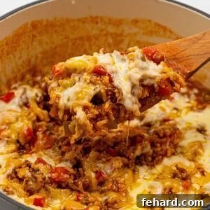 Spoon scooping out cheesy stuffed pepper casserole from a pan.
