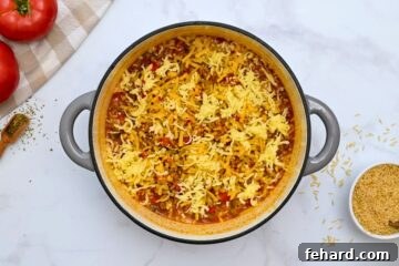 Stuffed Pepper Casserole with rice in large stock pan topped with cheddar and mozzarella cheese.