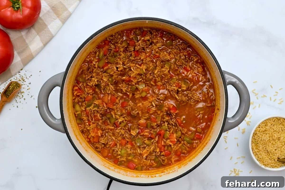 Easy Stuffed Pepper Casserole Cooked Lean ground beef, colorful bell peppers, and perfectly cooked brown rice in a rich tomato sauce, resting in a stock pan.