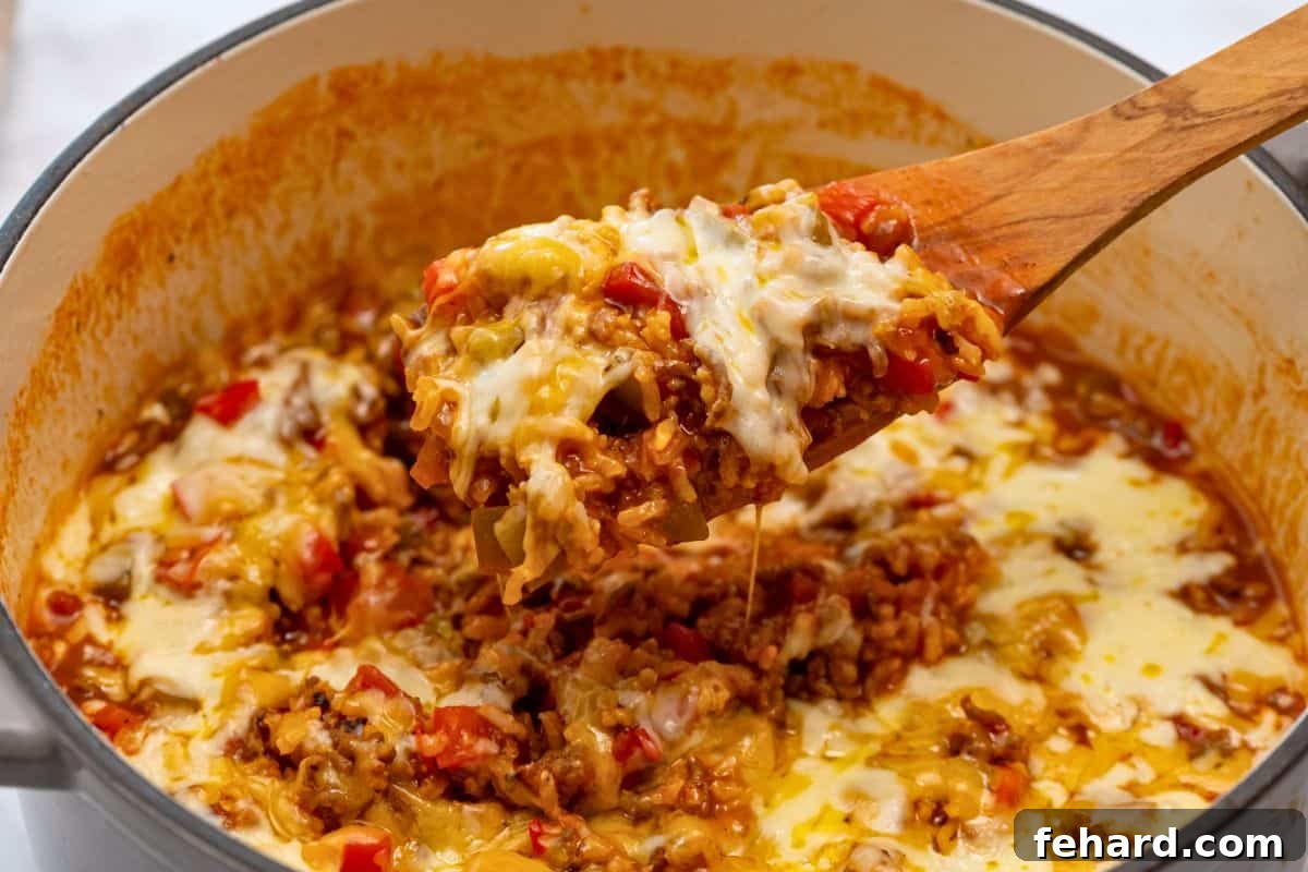 Stuffed Bell Pepper Casserole Scoop A large scoop of cheesy stuffed bell pepper casserole with visible green and red bell peppers being lifted from a large stock pan, ready to serve.