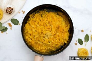 Skillet with fettuccine tossed with brown butter pumpkin sauce.