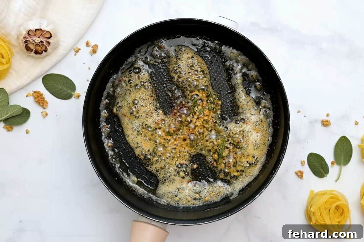 A skillet showcasing the aromatic blend of lightly golden brown butter, vibrant sage leaves, fiery crushed red pepper flakes, and minced garlic, toasting gently.