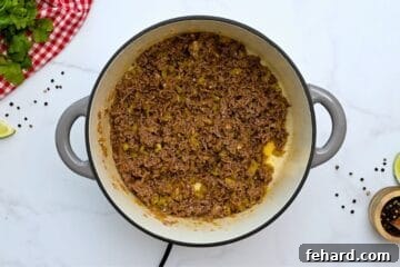 Ground beef and onions cooked with taco seasoning and green chiles in large Dutch oven for base of taco soup.