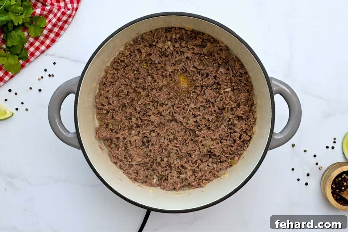Ground beef and yellow onion cooked together in a large deep soup pan, forming a savory base for taco soup.