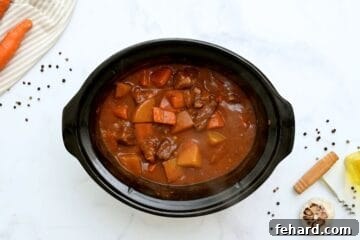 Beef Stew with potatoes and carrots in slow cooker after slow cooking but before being thickened.